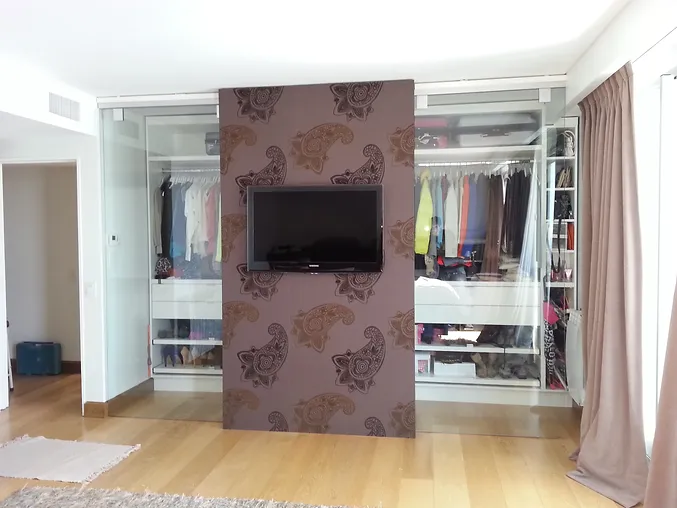 Vestidor de vidrio detrás de pared en habitación con televisor